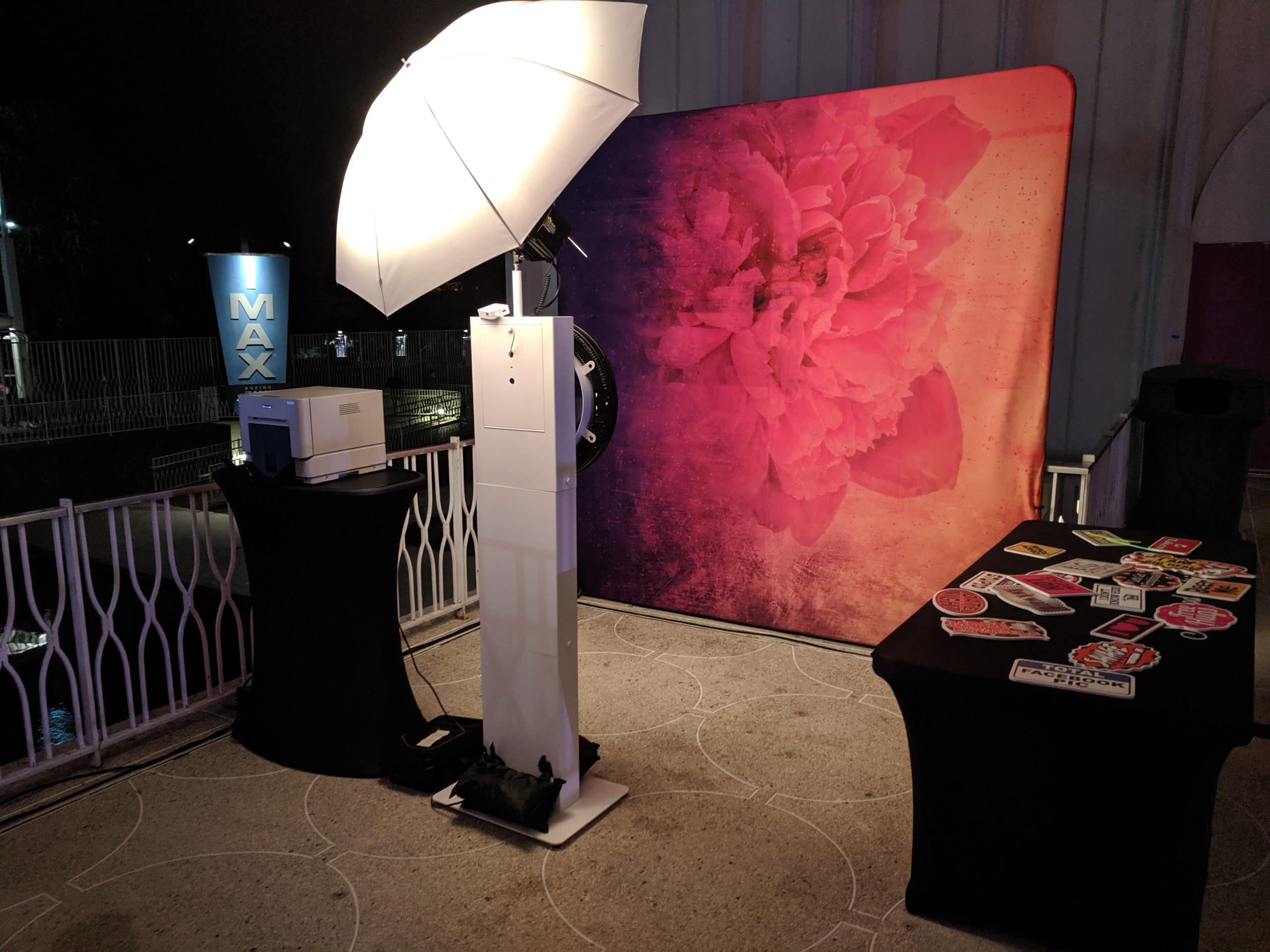 Classic Photo Booth with umbrella light and pink floral backdrop at outdoor evening event