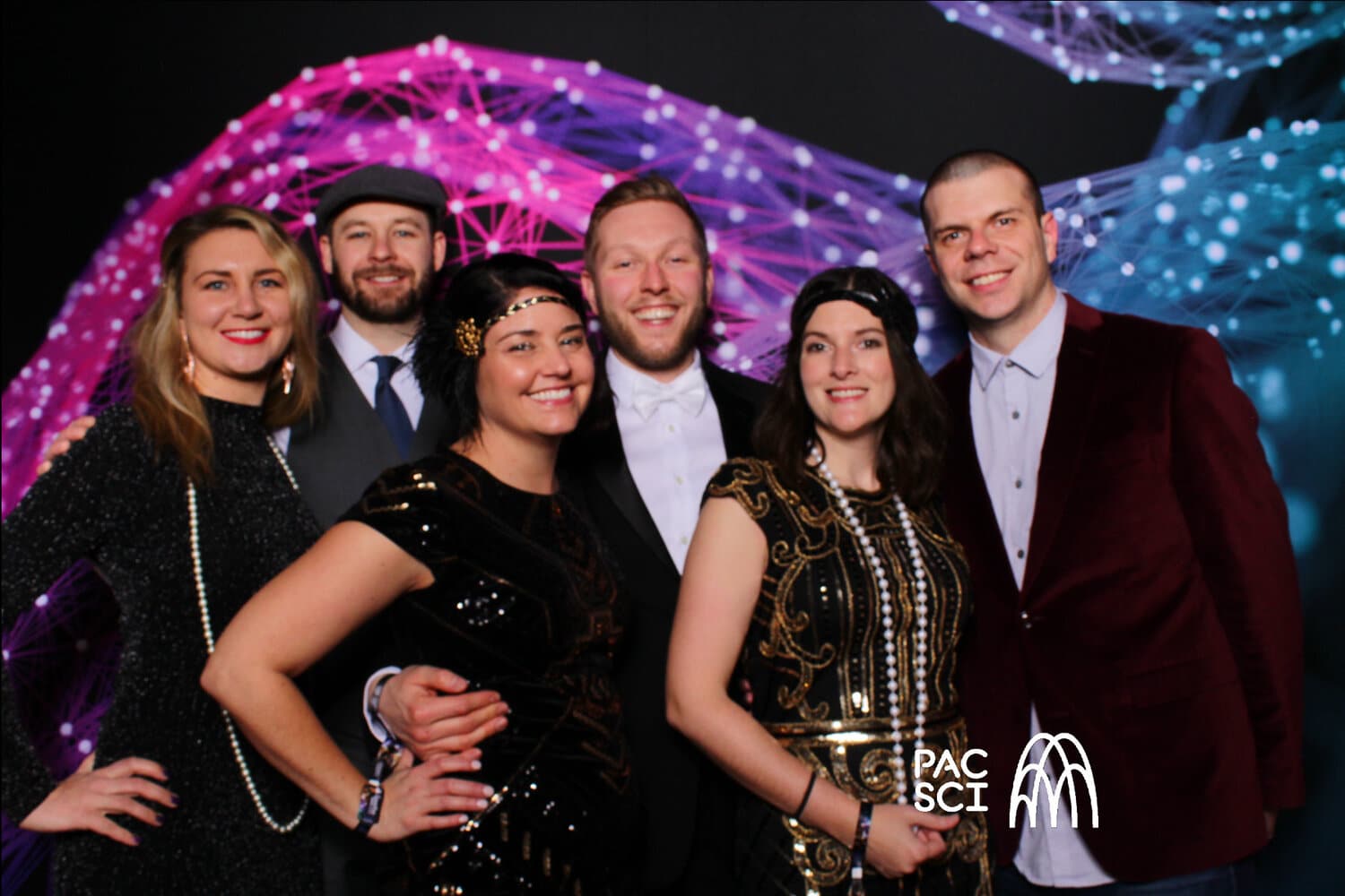 Group in 1920s Gatsby attire posing in front of fiber optic backdrop