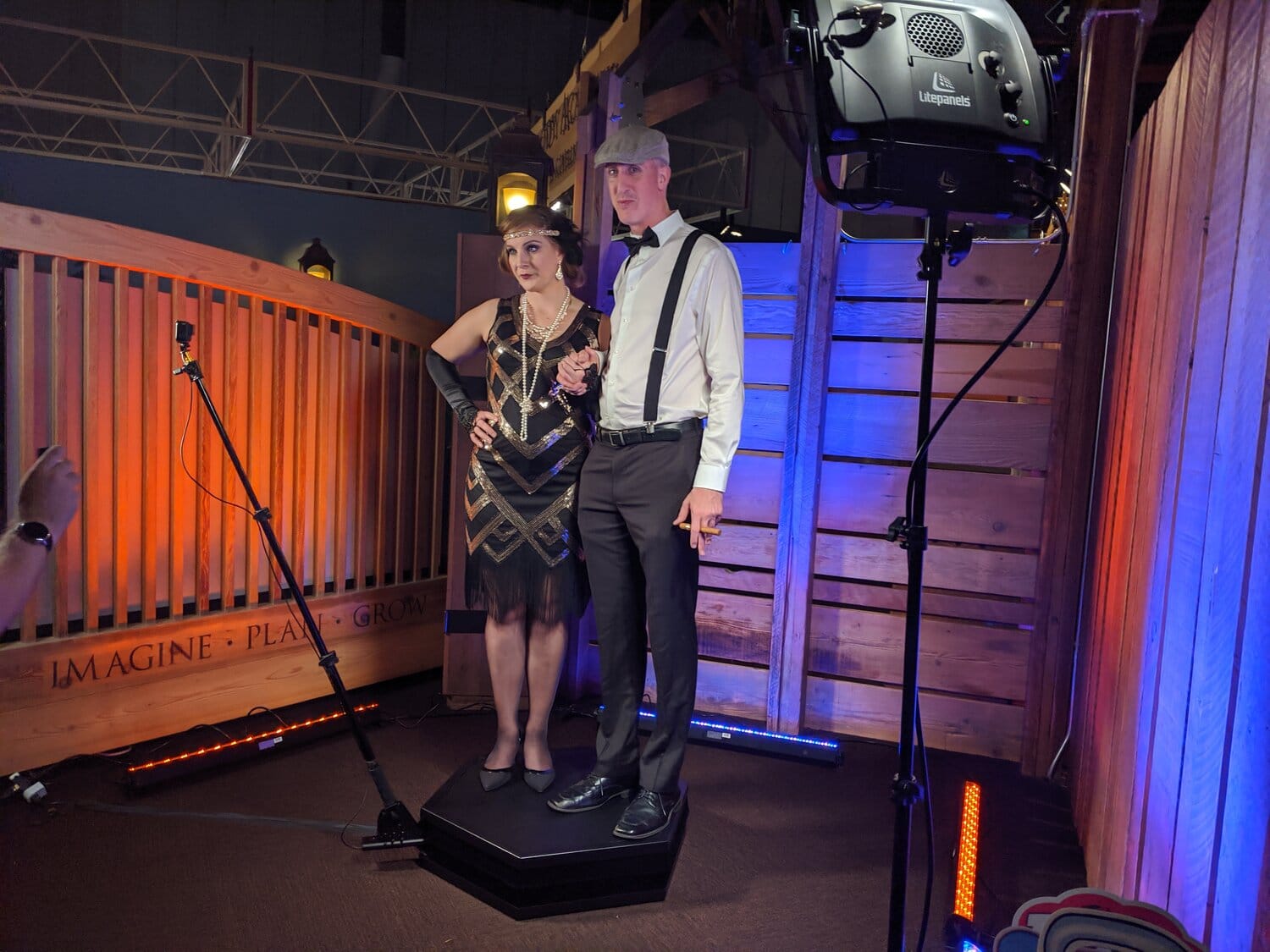 Couple in 1920s attire riding Orbit 360 photo booth platform at event