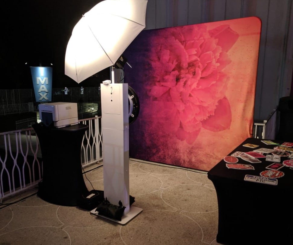 Classic Photo Booth with pink floral backdrop, MAX monitor and prop table outdoors