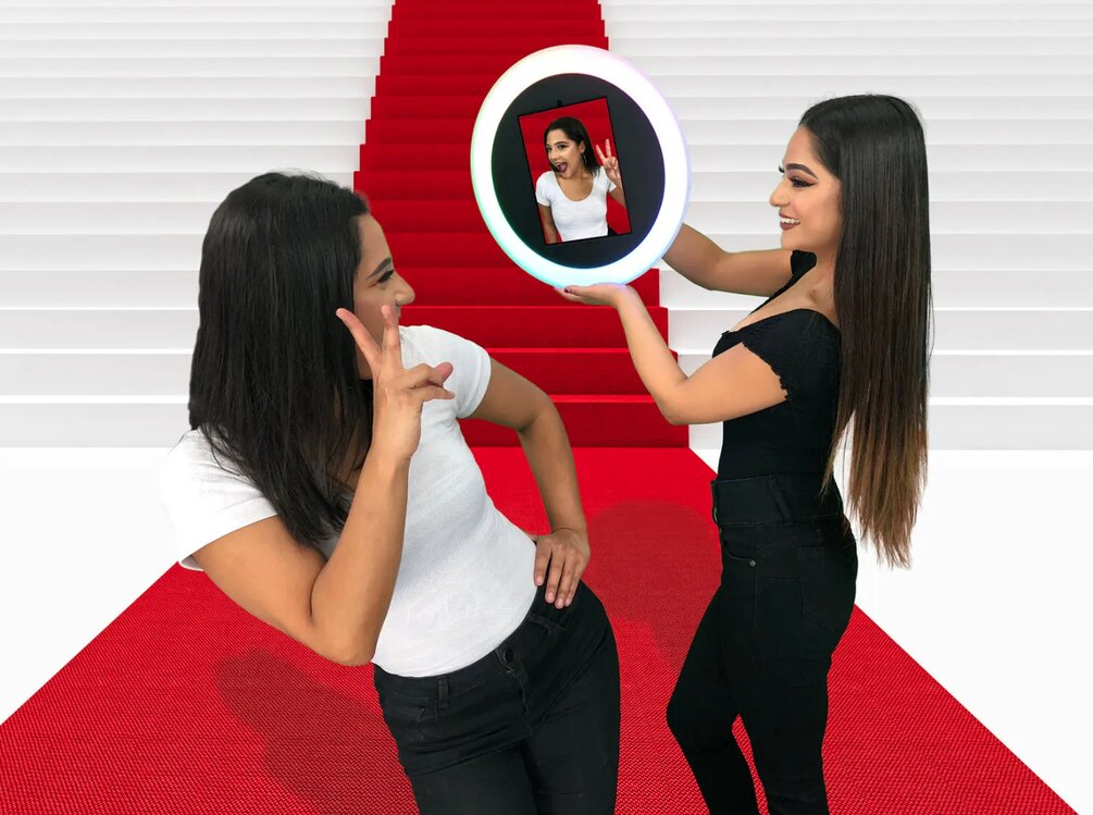 Two women on red carpet posing with Freeform Roaming Booth handheld ring camera