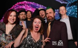 Group of friends laughing at vintage photo booth with sparkling fiber optic backdrop