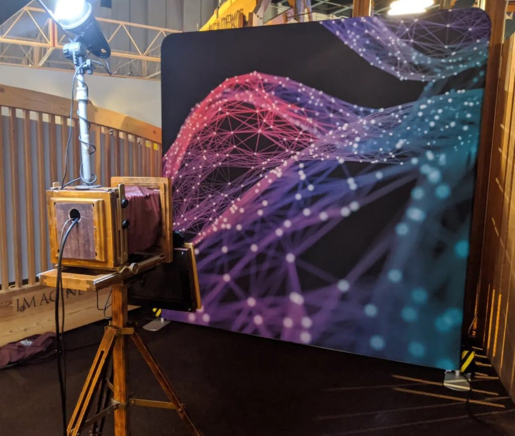 Vintage wooden camera booth facing purple geometric mesh backdrop at event