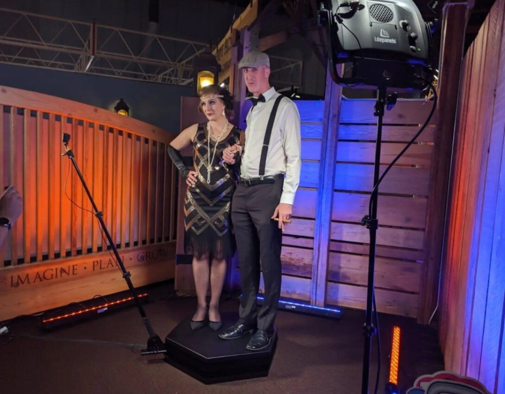 Couple in 1920s attire posing on Orbit 360 photo booth platform