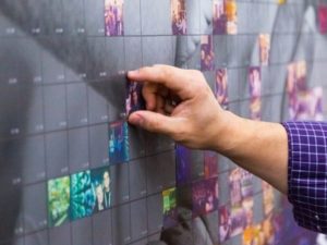 Hand pinning printed photo tile into Wall Mosaic display panel