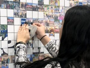 Woman placing printed photo tile into Wall Mosaic at corporate event