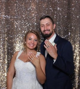 Bride and groom posing in front of gold sequin photo booth backdrop