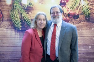 Couple smiling together in front of rustic holiday-themed photo booth backdrop