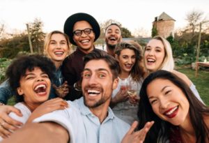 Group of friends laughing together for an outdoor selfie at garden party