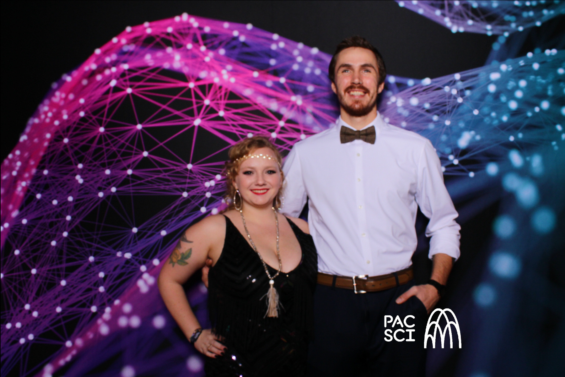 Couple in formal attire posing at vintage photo booth with fiber optic backdrop