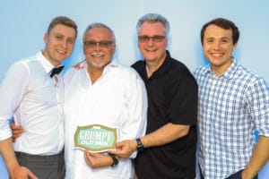 Group of men in formal attire holding Grumpy Old Men sign at photo booth