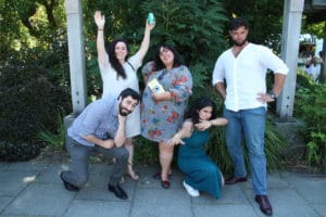 Group of friends posing playfully outside under garden trellis at event