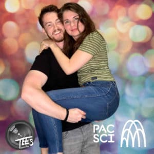 Couple smiling and embracing at photo booth with colorful bokeh backdrop
