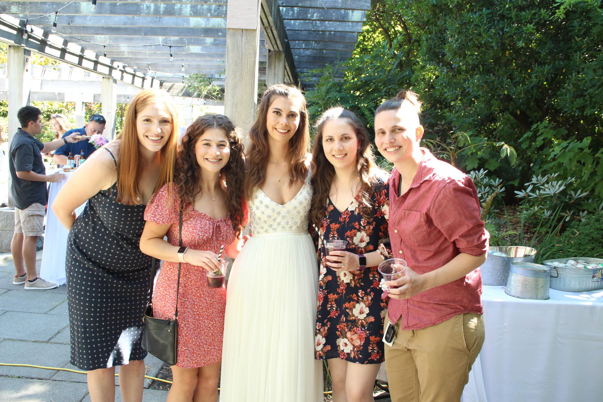 Group of women in summer dresses smiling at outdoor garden wedding