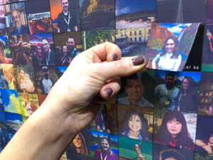 Hand placing photo tile into Wall Mosaic display panel up close