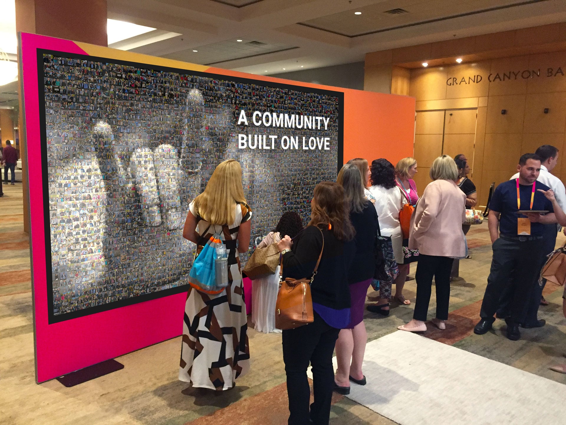 Guests viewing Wall Mosaic photo collage display reading A Community Built On Love