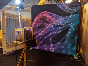 Vintage wooden camera booth facing purple geometric mesh backdrop at event
