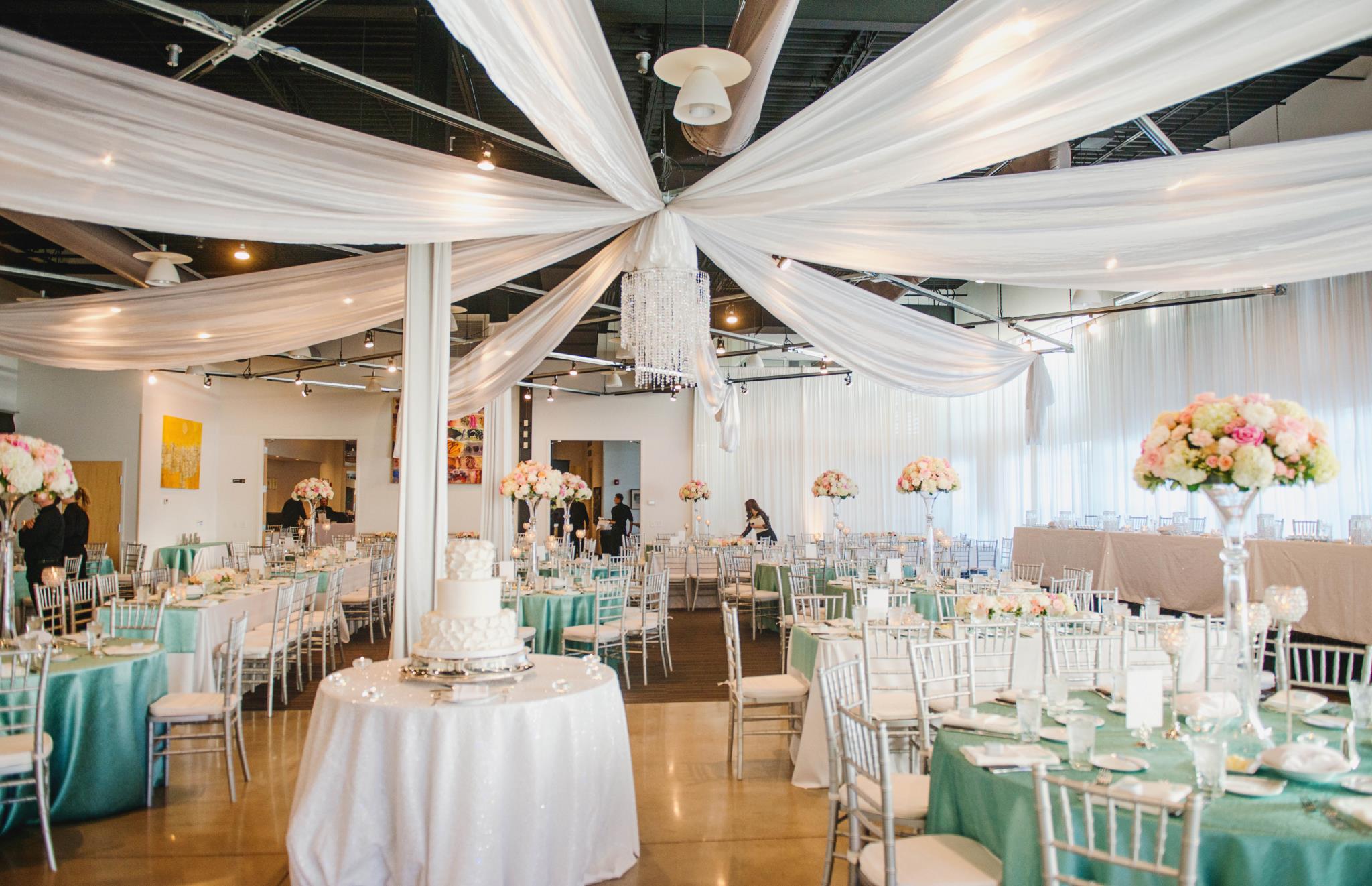 Embassy Club ballroom set with white draping and teal-themed wedding tables
