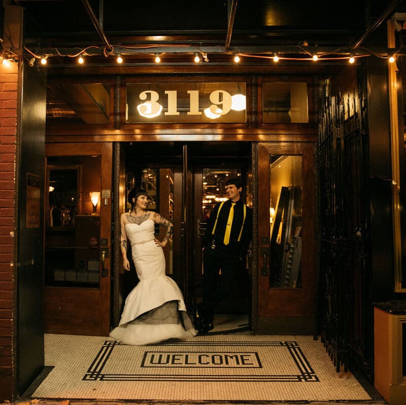 Bride and groom standing at Imperia restaurant entrance with welcome doormat