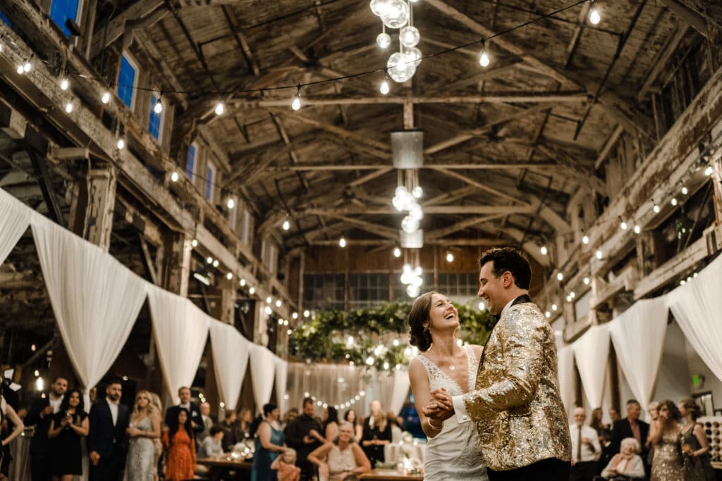 Bride and groom dancing under string lights inside Sodo Park warehouse venue
