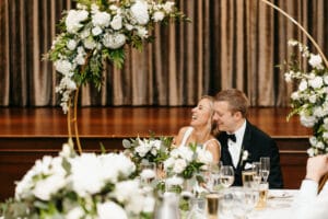 Bride and groom seated at Tea Room head table with floral arrangements