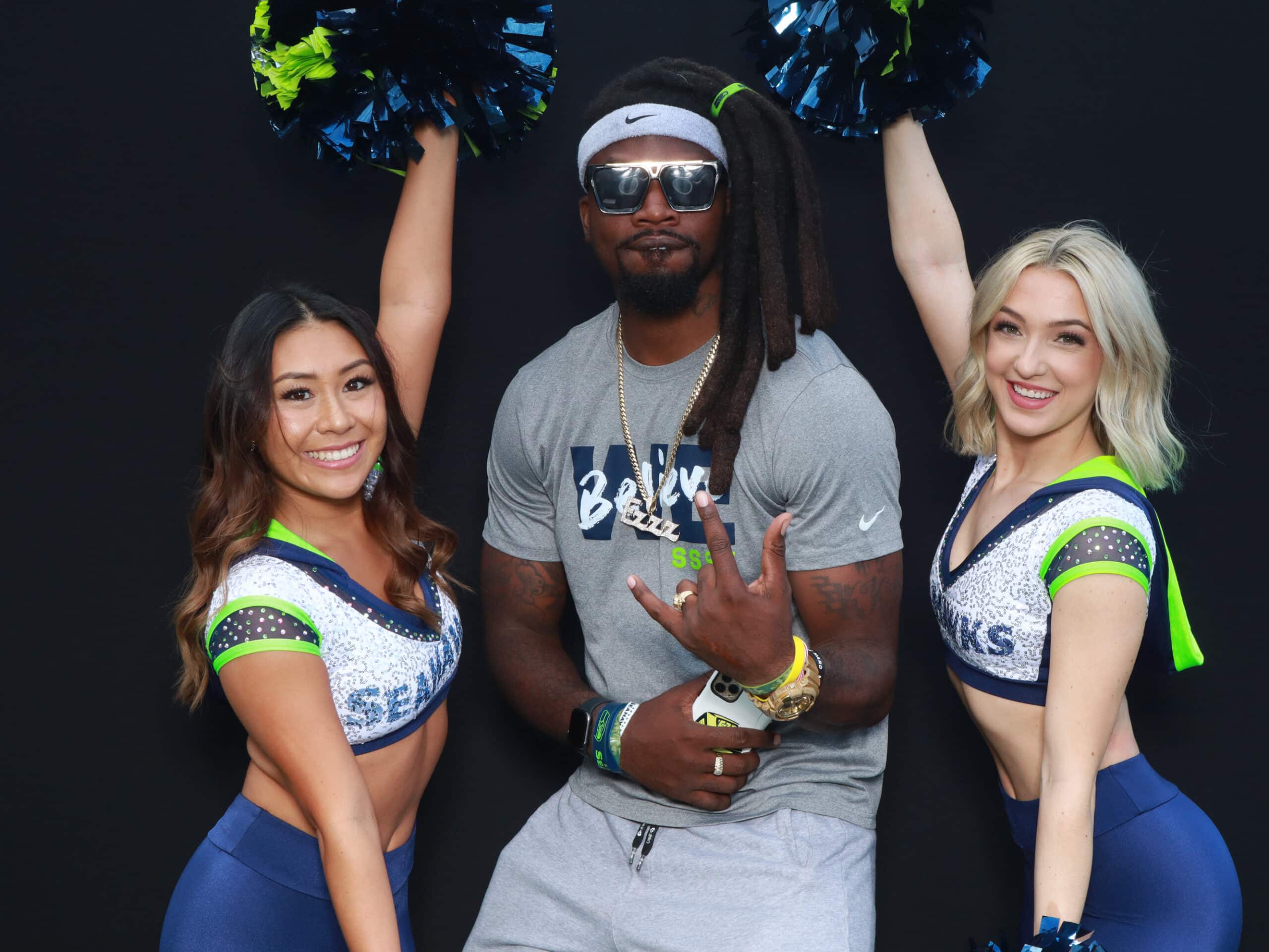 Seahawks player posing with two cheerleaders holding pom-poms at sports themed booth