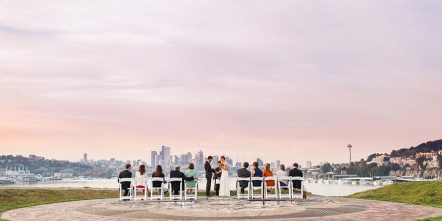 Outdoor wedding ceremony at Gas Works Park overlooking Seattle skyline at dusk