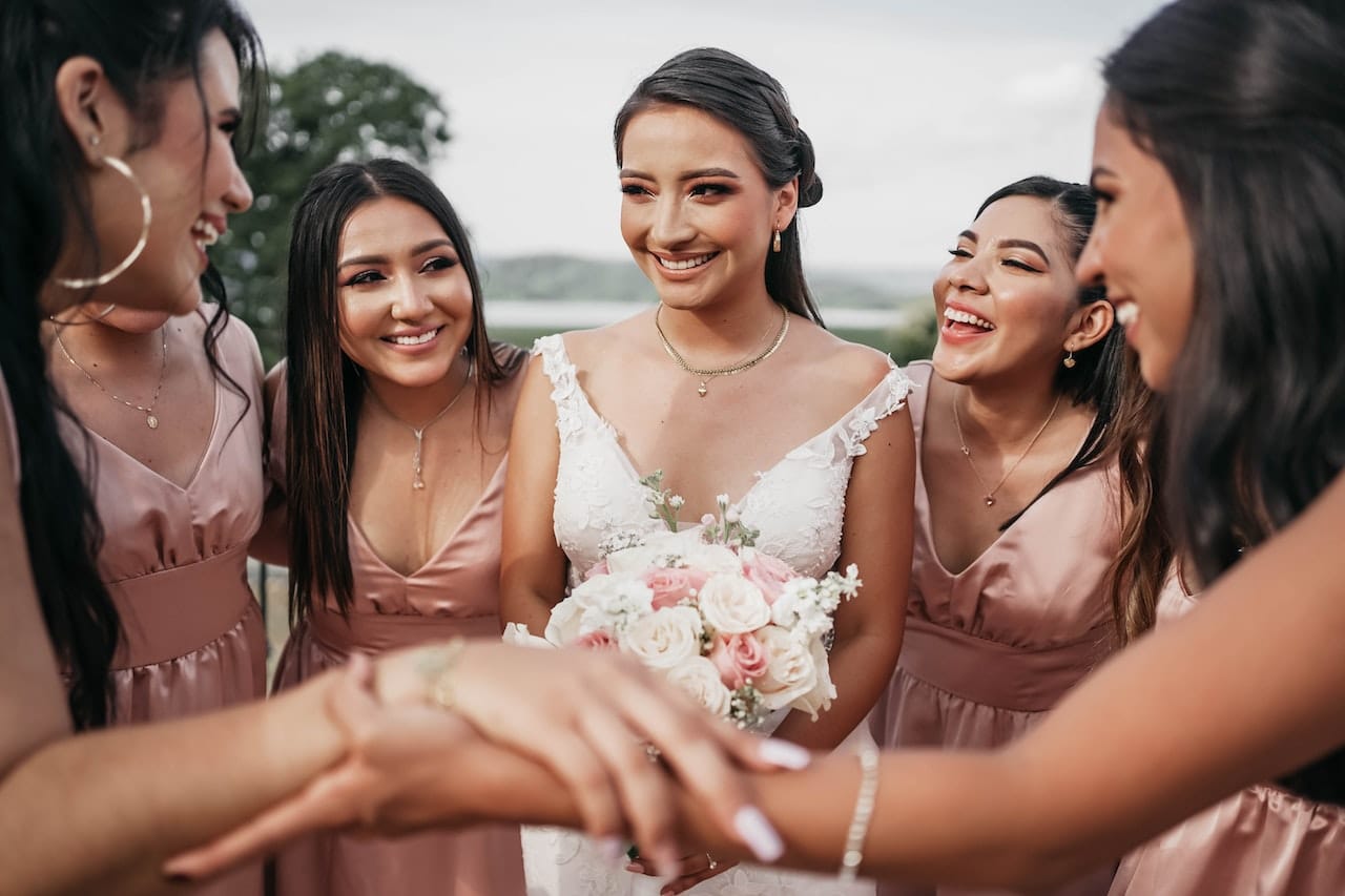 Bridesmaids and bride laughing together at outdoor wedding with bouquets