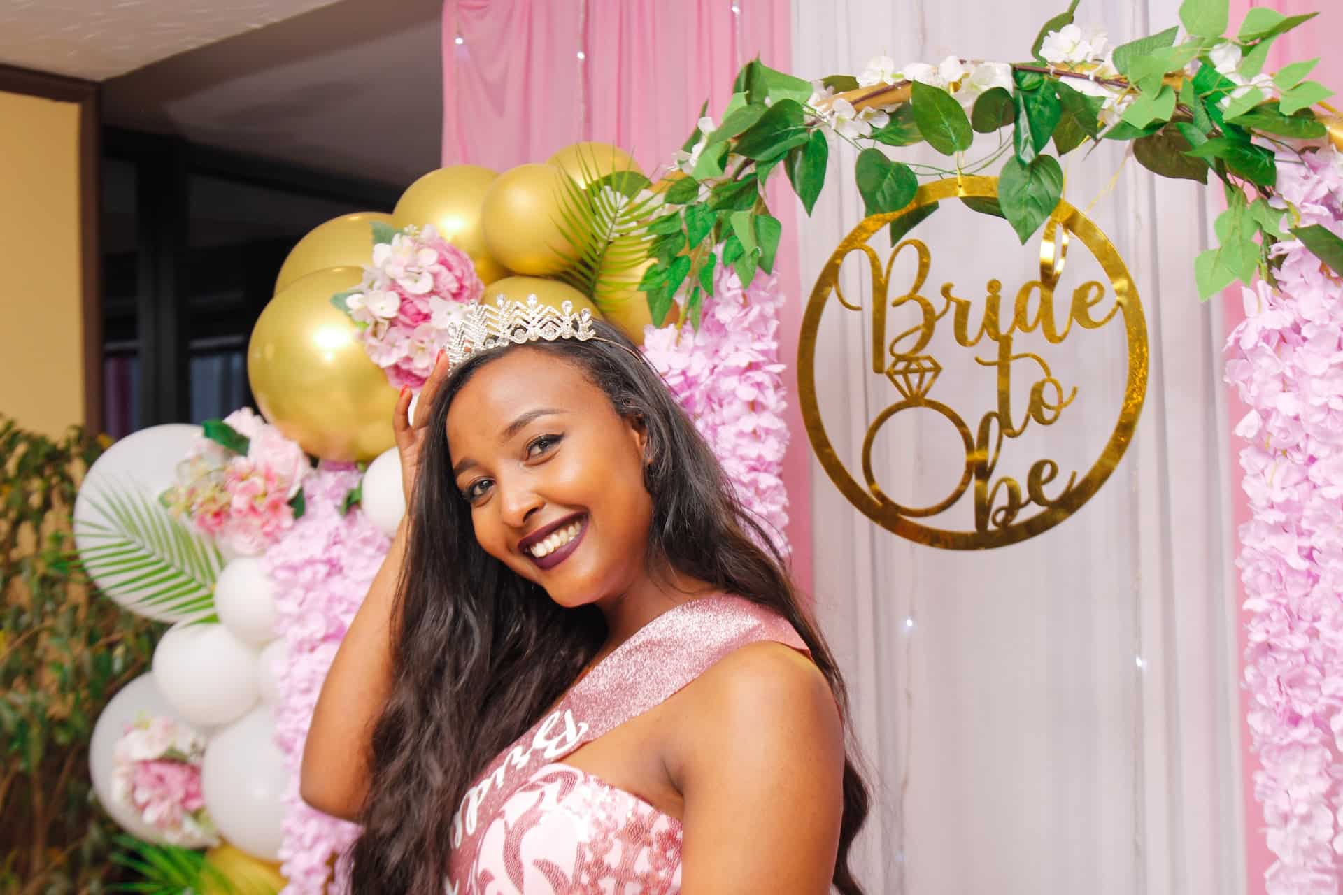 Smiling woman in floral crown at pink Bride To Be balloon backdrop