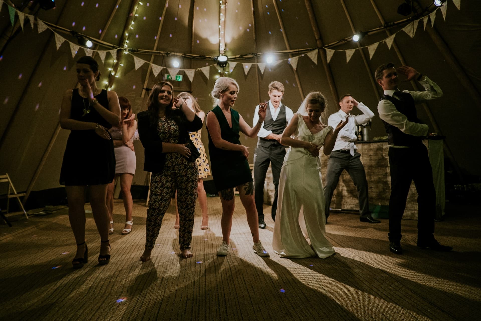 Bride and groom dancing surrounded by guests in tipi tent wedding venue