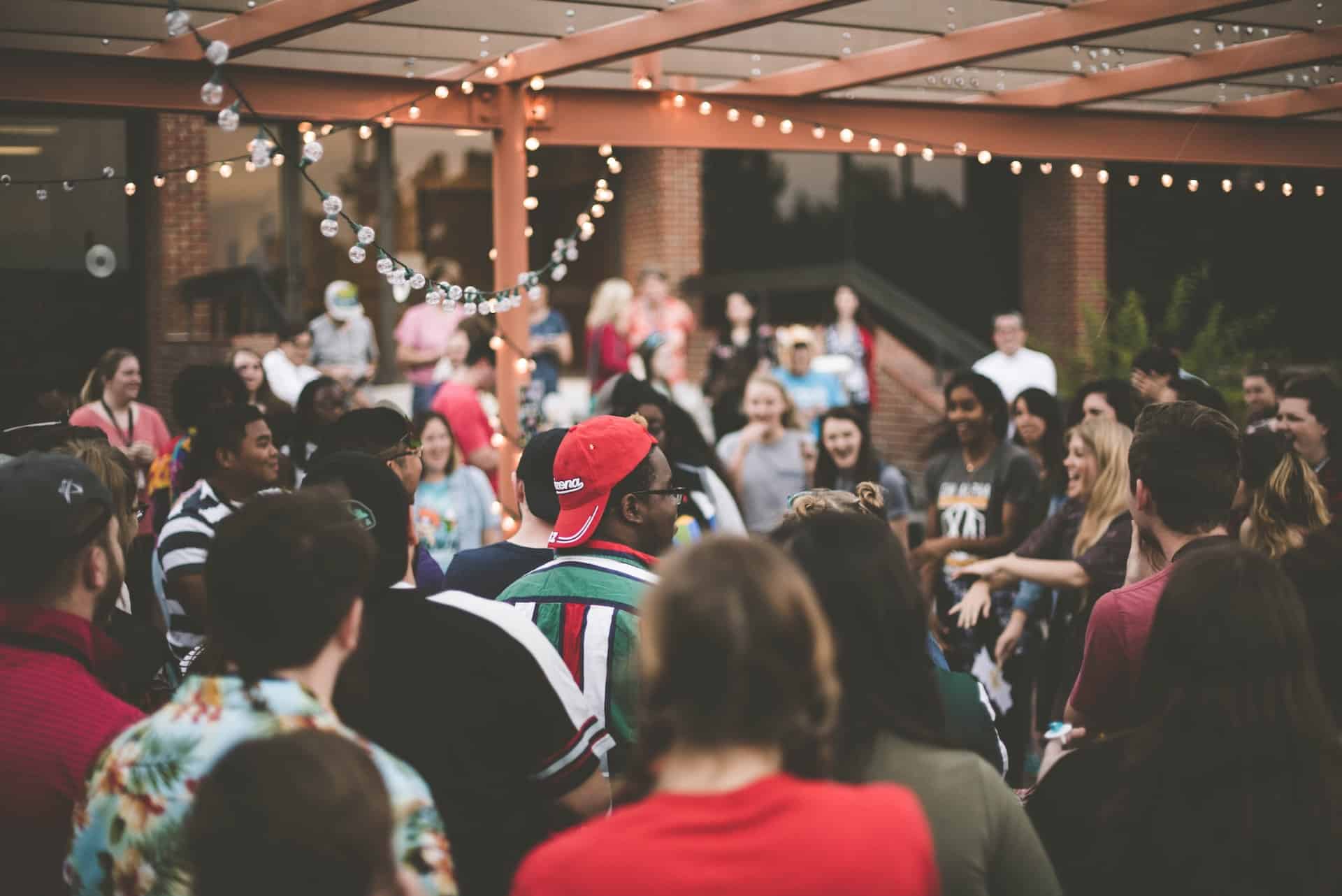 Crowd gathered at outdoor evening event with string lights overhead