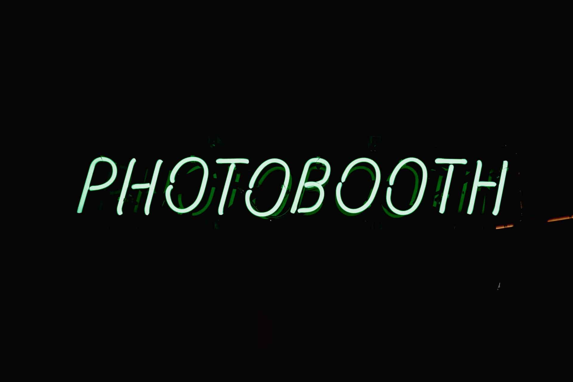 Green neon Photobooth sign glowing on dark background