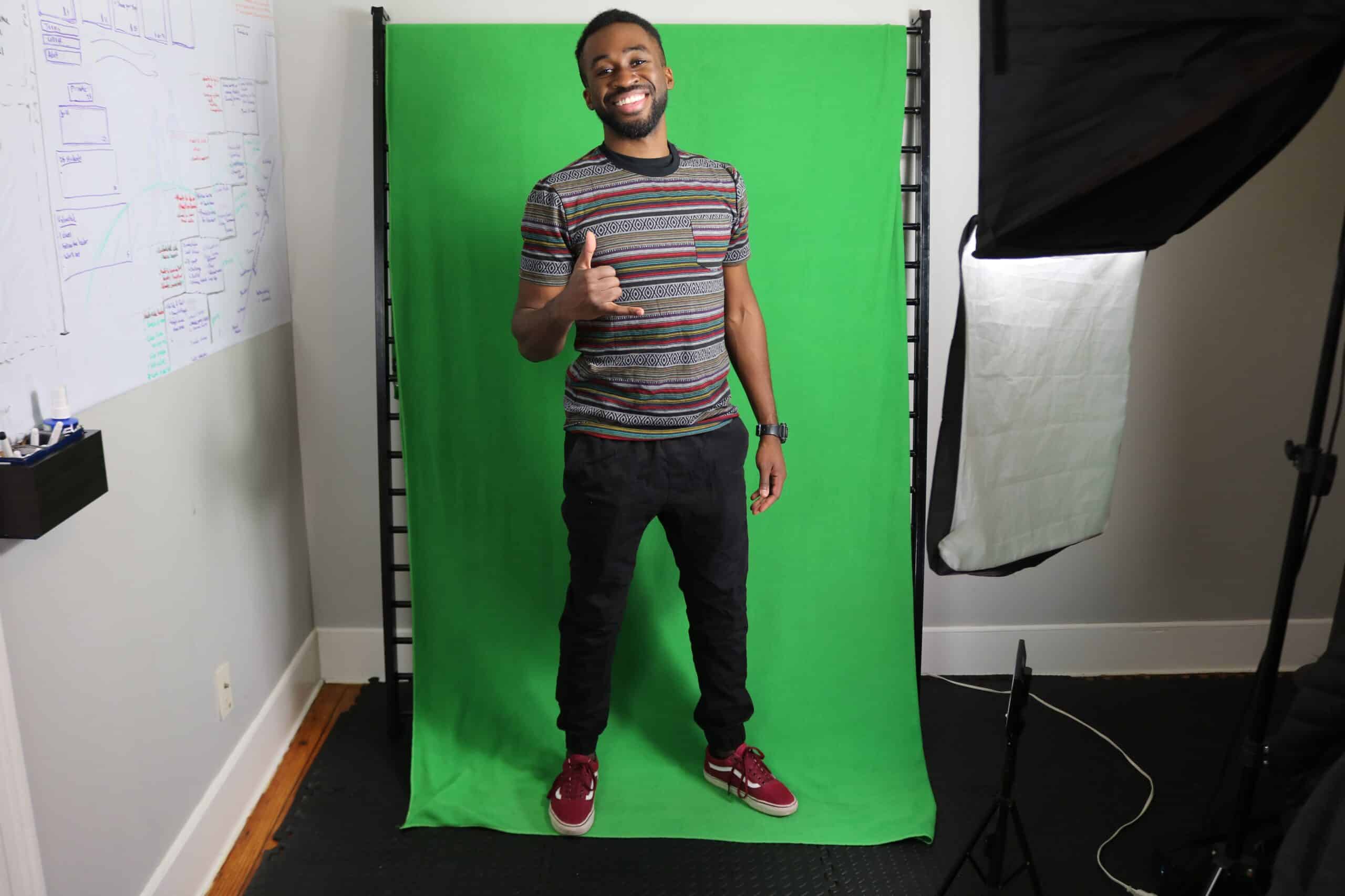 Man giving thumbs up posing in front of green screen photo studio backdrop