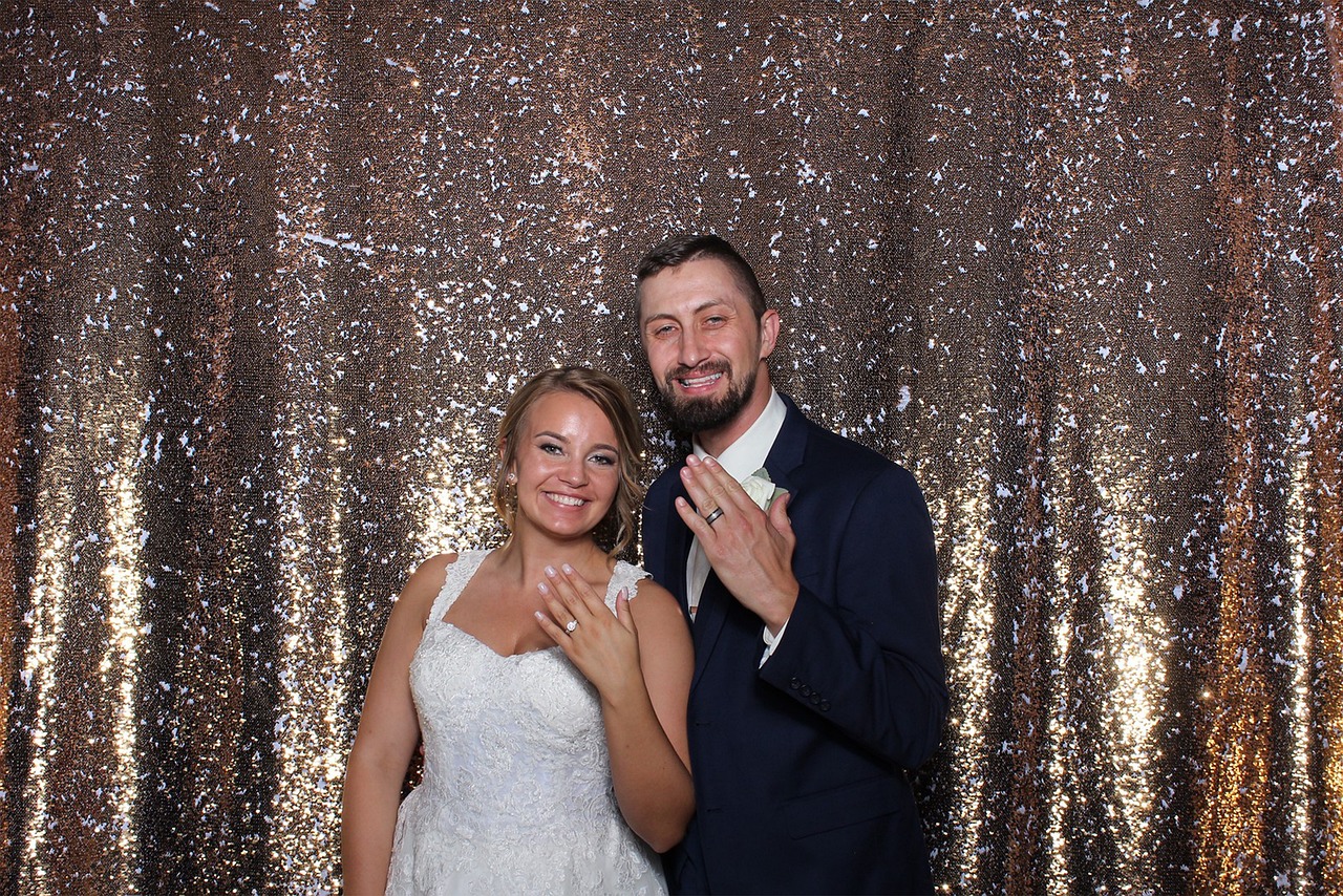 Bride and groom celebrating with sparklers at gold sequin photo booth backdrop