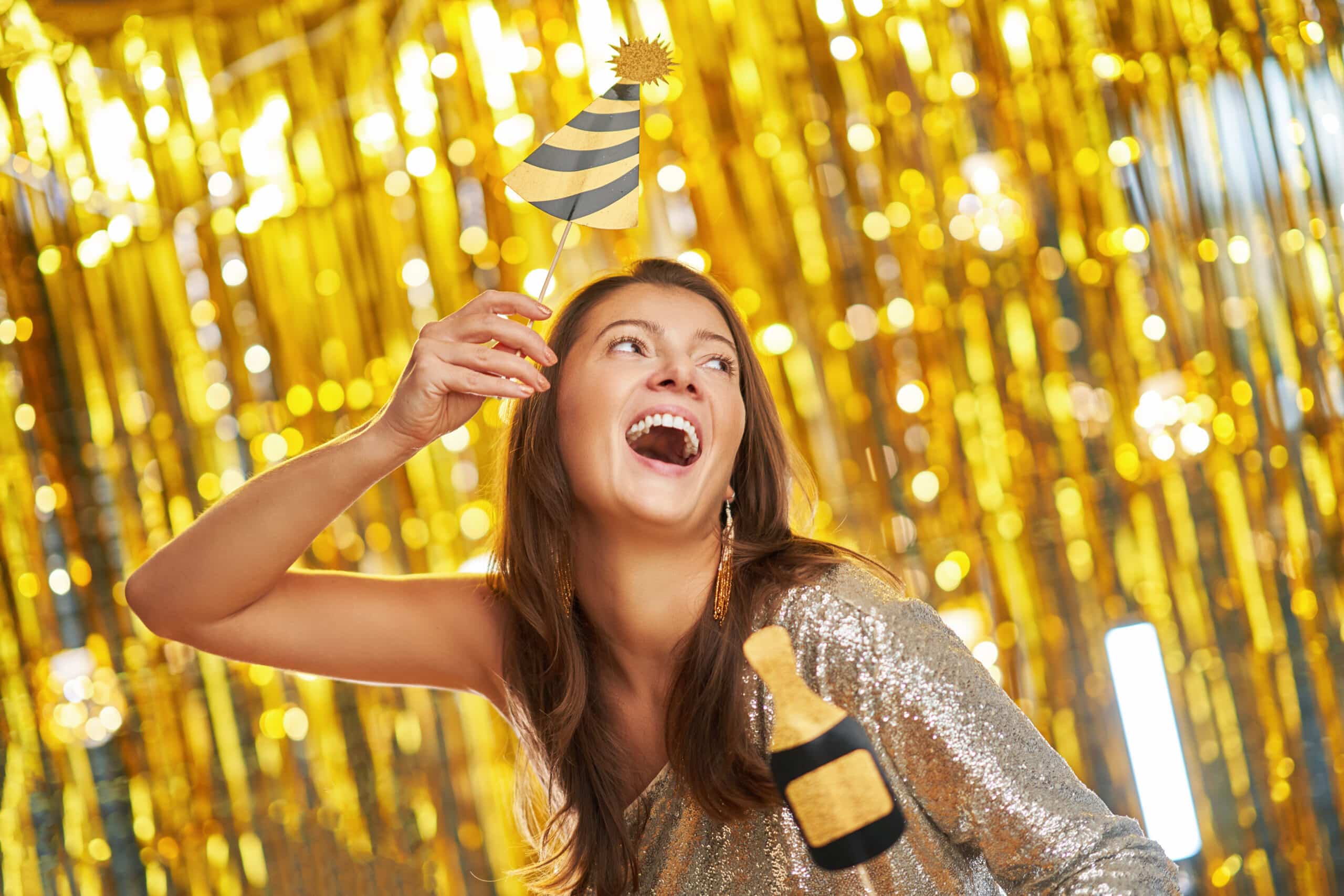 Woman in sequin dress laughing with star prop at gold metallic curtain backdrop