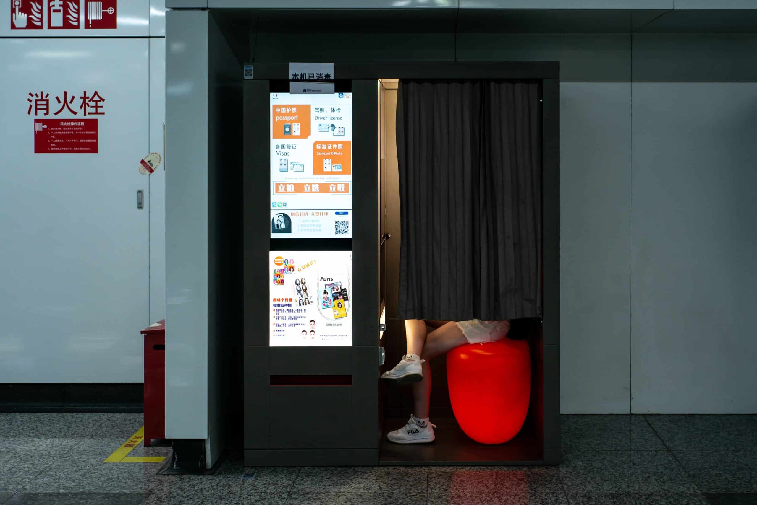Vintage style photo booth with curtained doorway and red stool inside transit station