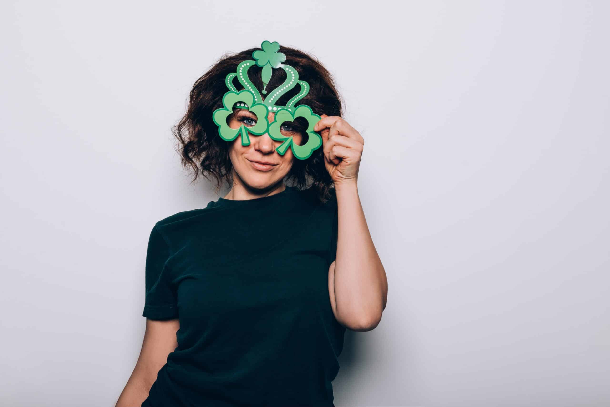 Woman holding green dollar sign mask prop at white photo booth backdrop