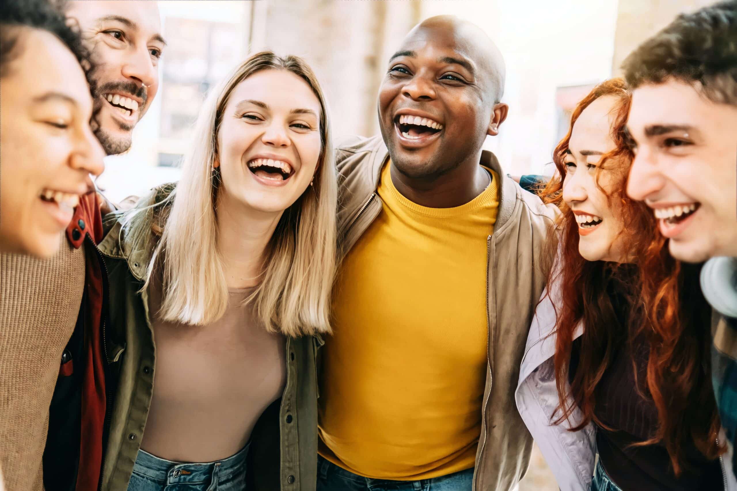 Group of multicultural friends laughing together outside in casual setting
