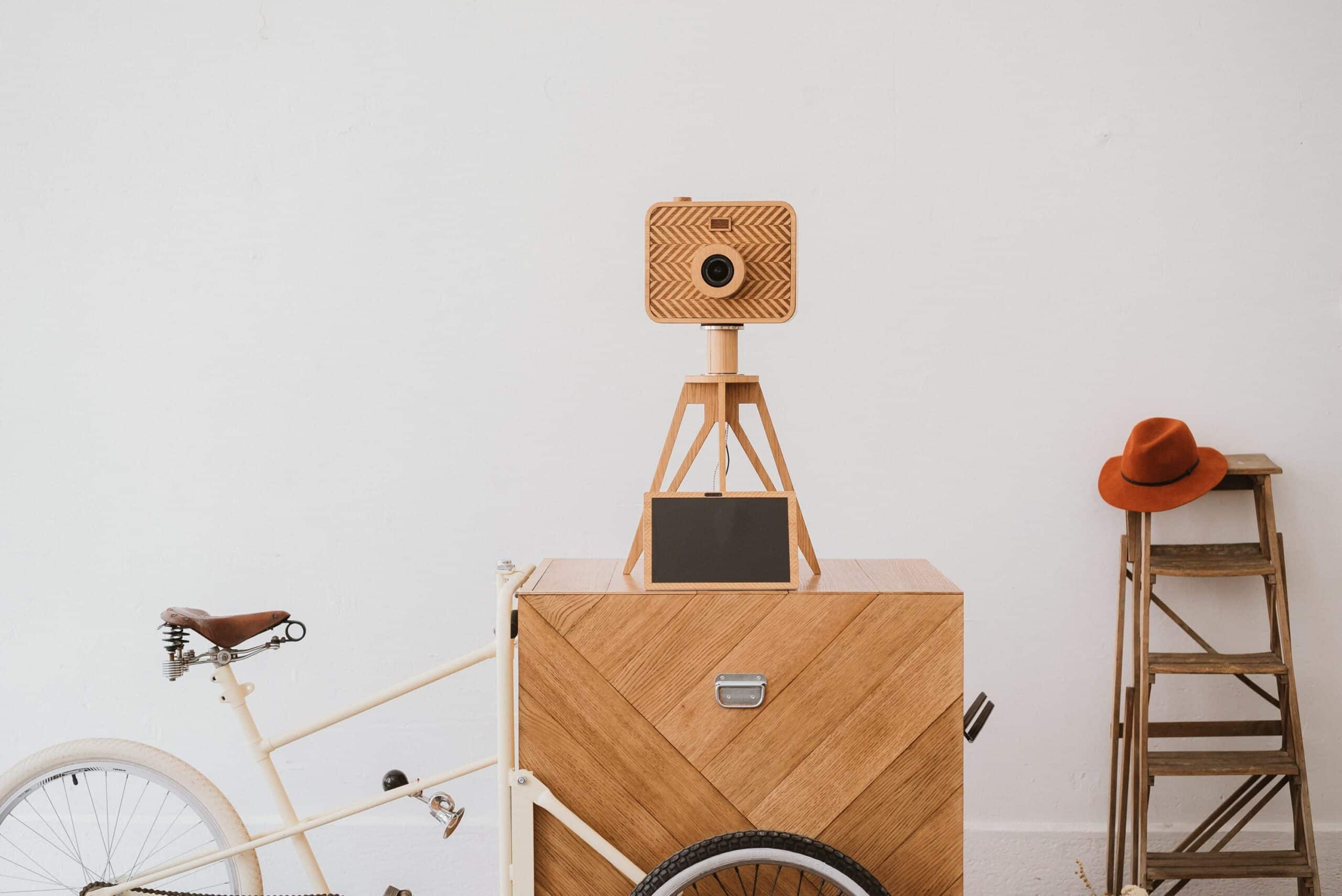 Vintage style wooden box camera on cart with bicycle and stool nearby