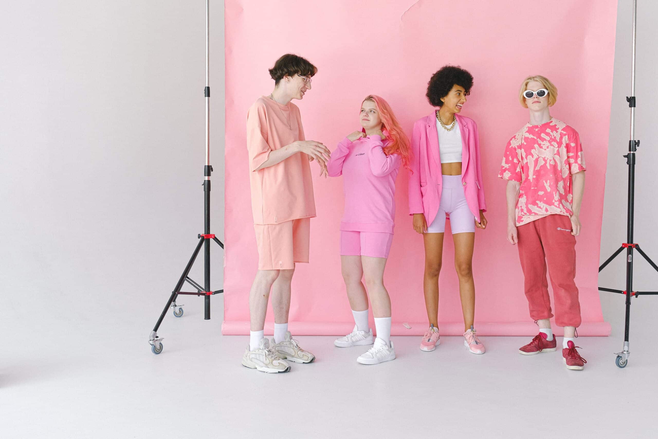 Four people in coordinated pink outfits posing at pink studio backdrop