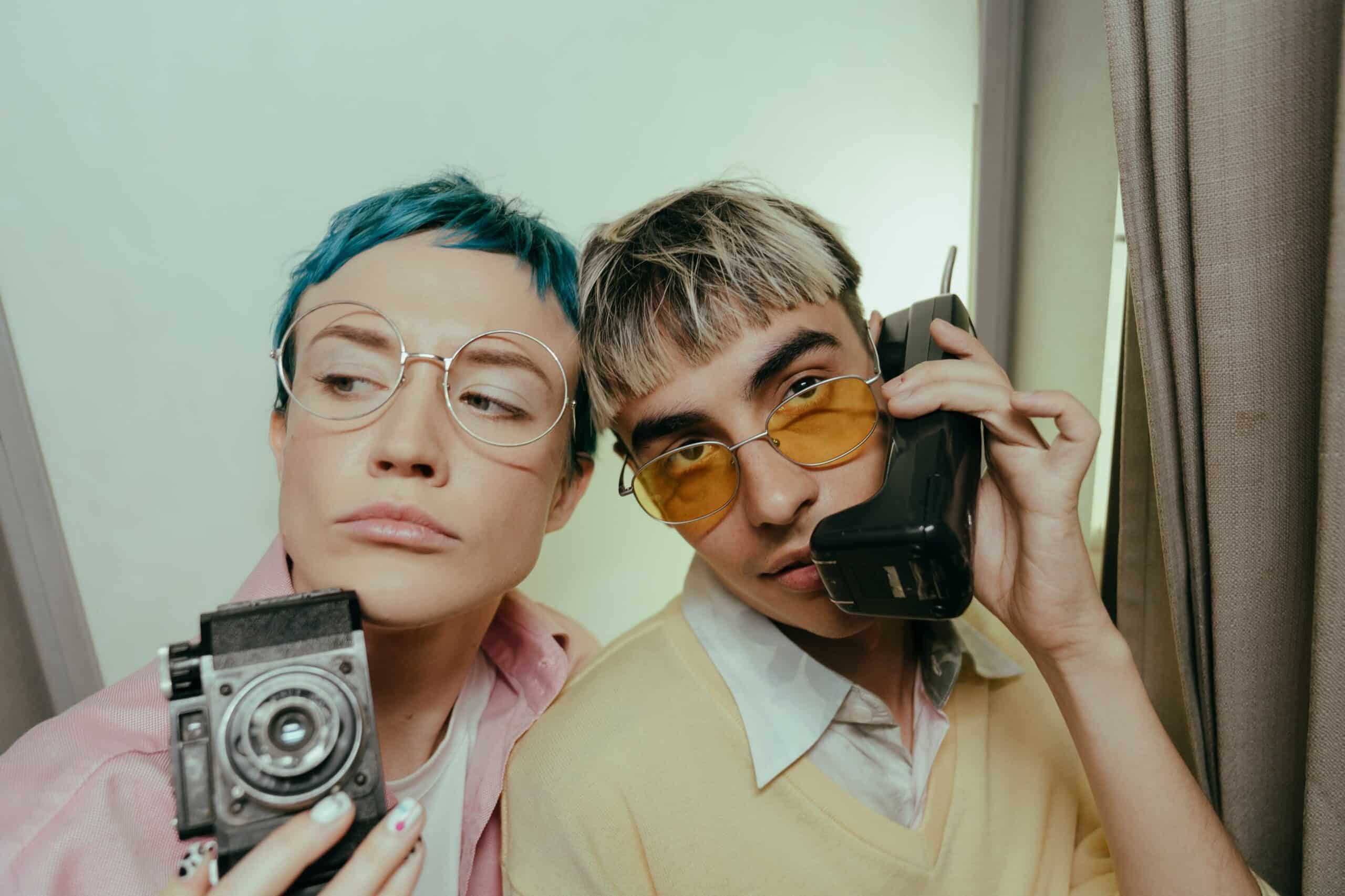 Two people with vintage camera and yellow phone in retro photo booth setting