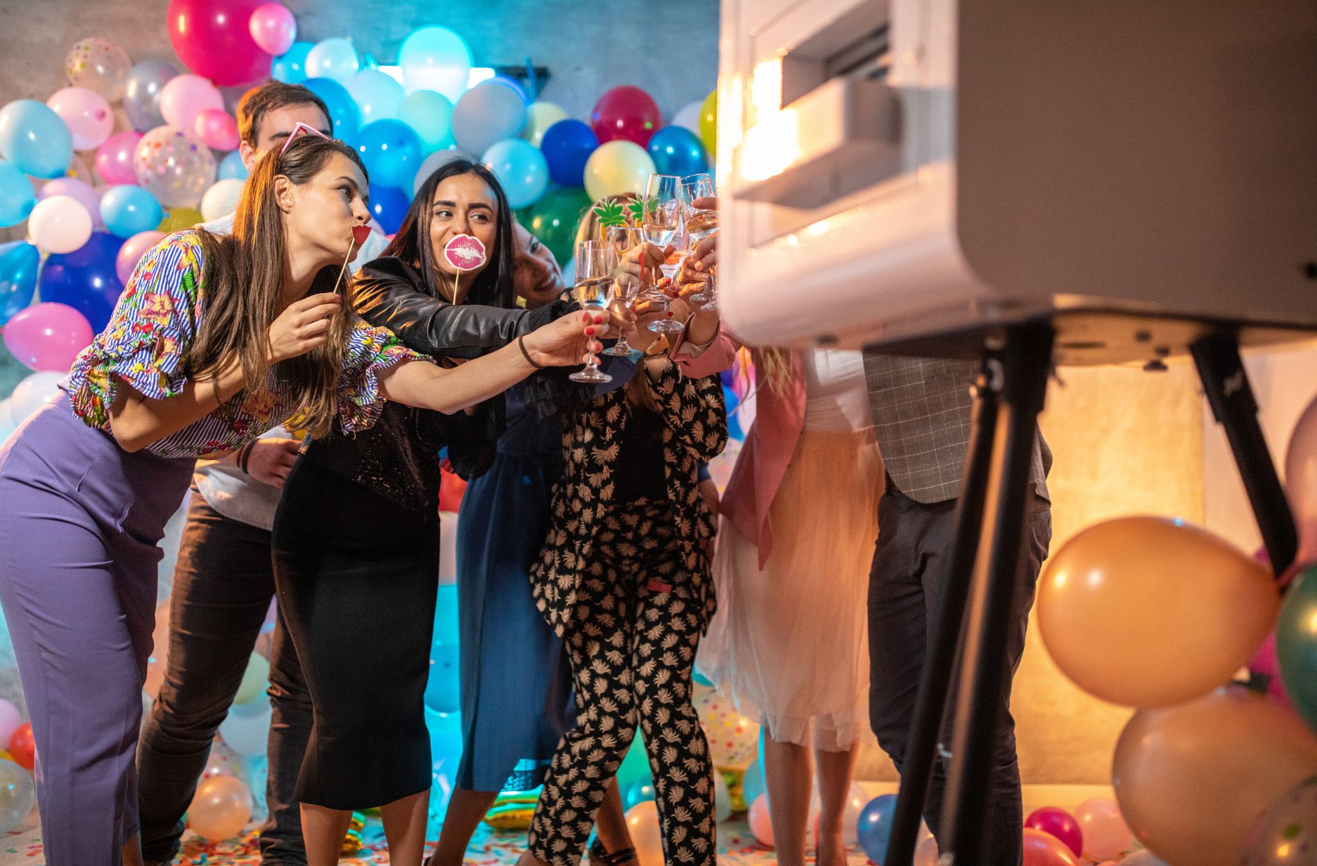 Group of women in formal attire at photo booth with balloon decor
