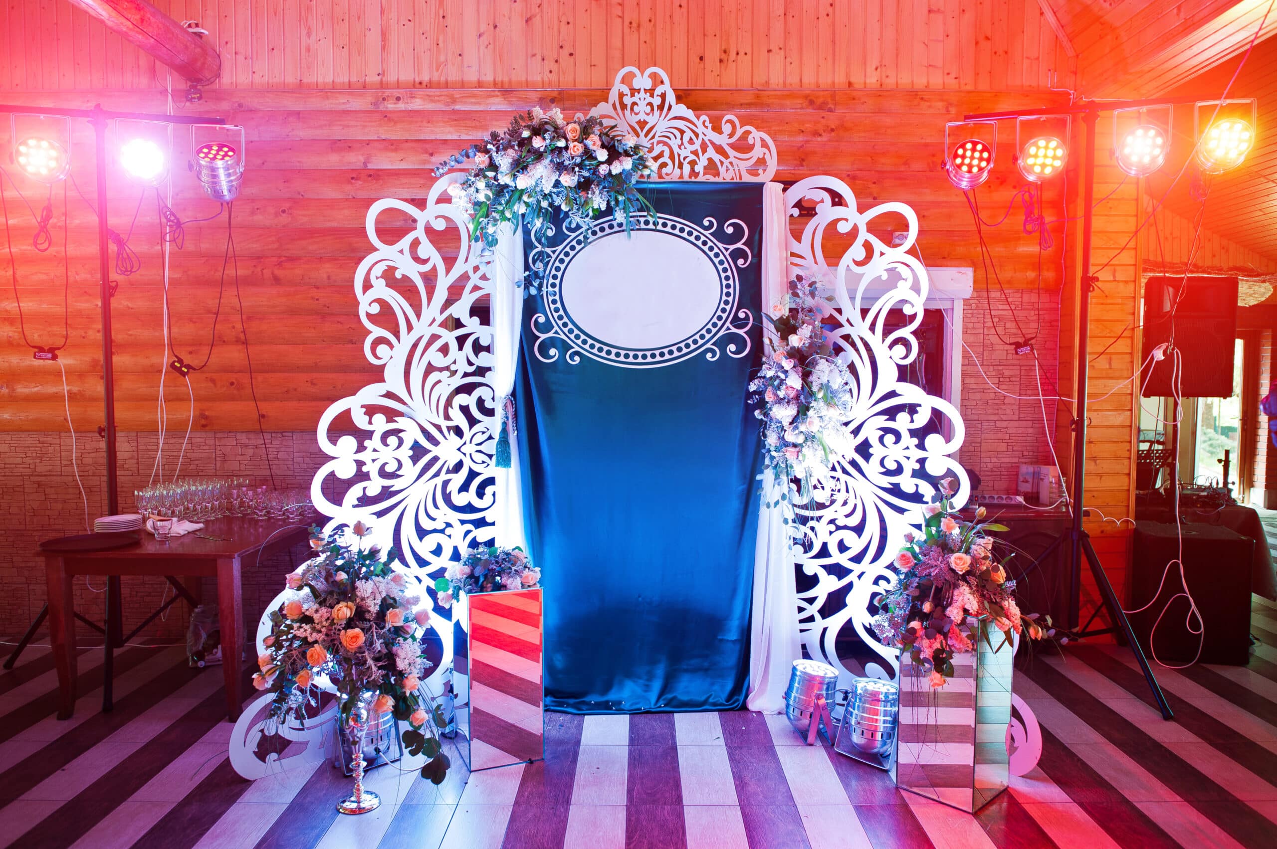 Ornate ornamental photo booth backdrop with white scrollwork frame and floral accents