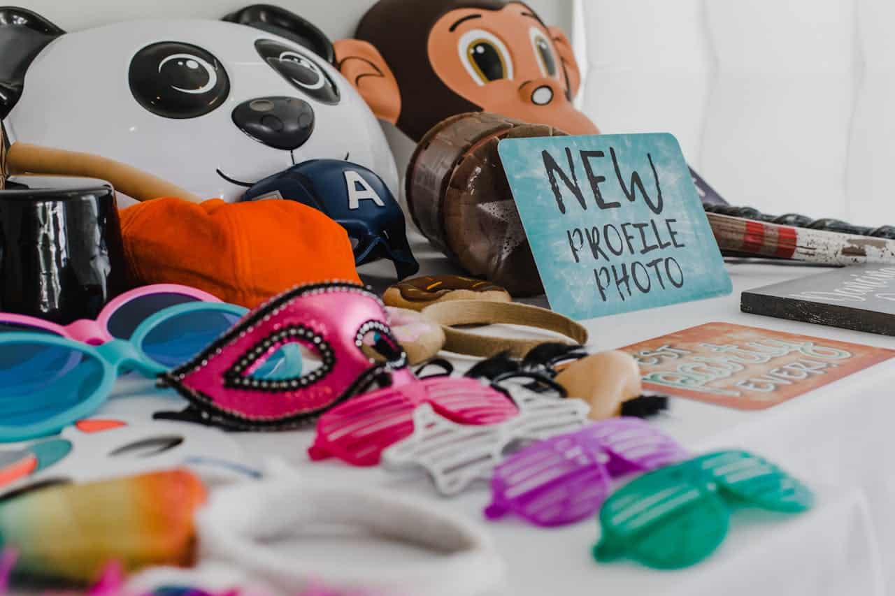 Table of photo booth props including masks, sunglasses and New Profile Photo sign